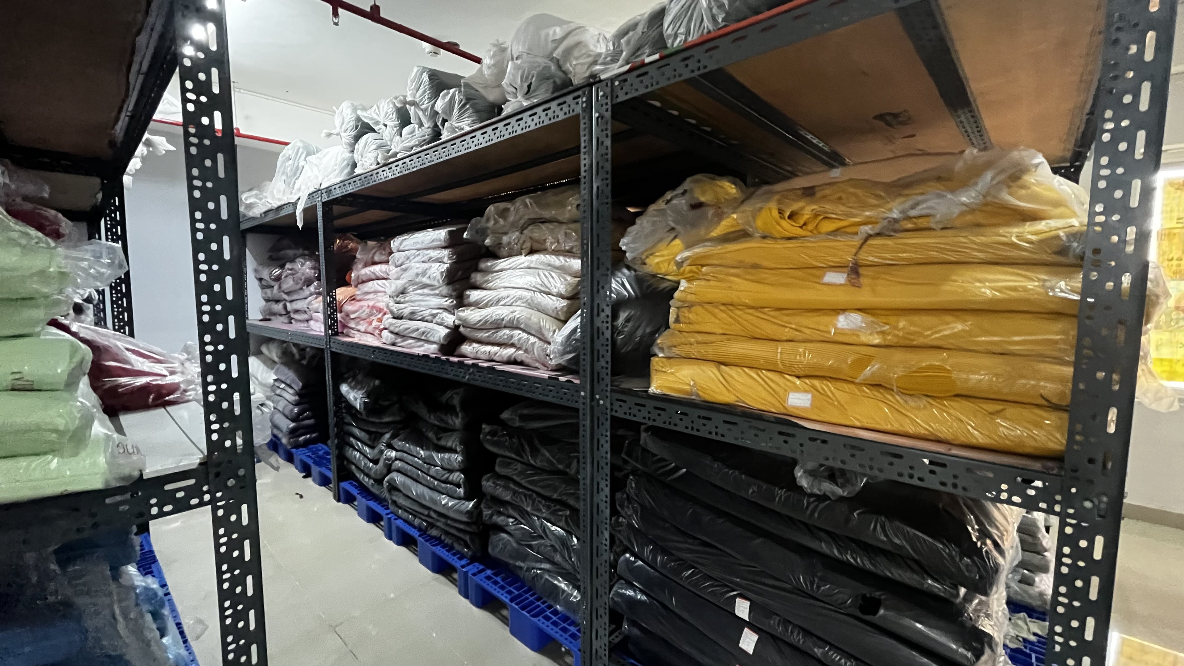 Temperature-controlled fabric storage housing 10+ tonnes of undyed fabrics and 20,000 kgs of dyed fabrics, ready for immediate production. Plakads Fabric Storage Area with Organized Inventory